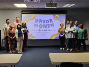 CCA staff posing on left and ride side of projector screen; project screen reads "Pride Month Lunch and Learn"
